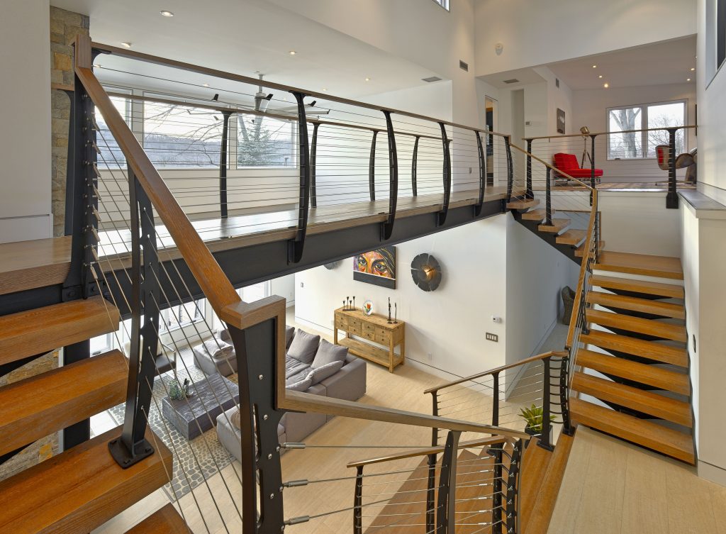 Double Split or Bifurcated interior staircase with stainless cable railing, and curved railing posts wrapping the stairs and catwalk.