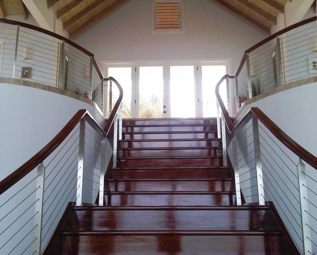 Antigua custom cable railing for interior staircase. Stainless steel stair railings with mahogany steps.