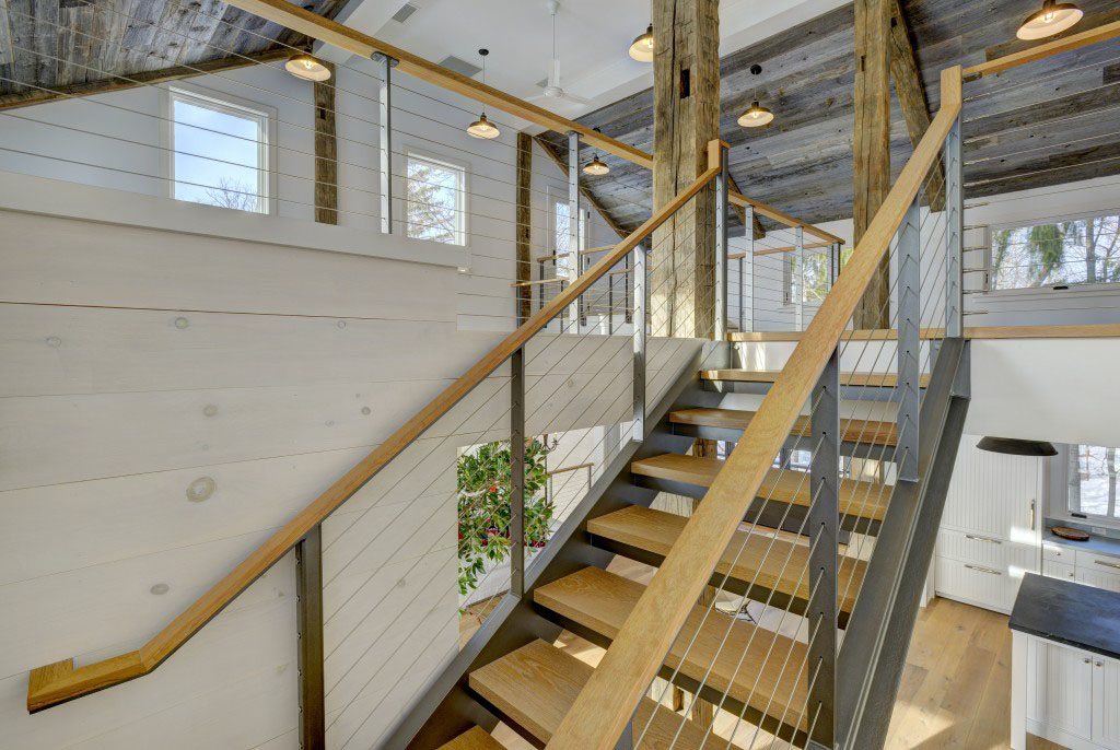 Interior of rustic party barn showcasing stairs in a channel style with cable railing post color dazzling pewter. 