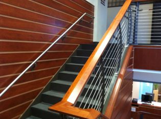 Teak and holly looking wall paneling accent this  staircase with a cherry banister