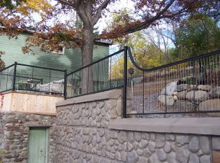 Vertical cable railing outdoor on stone retaining wall