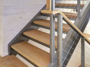 Wood handrail detail on this landing with stainless steel cables 