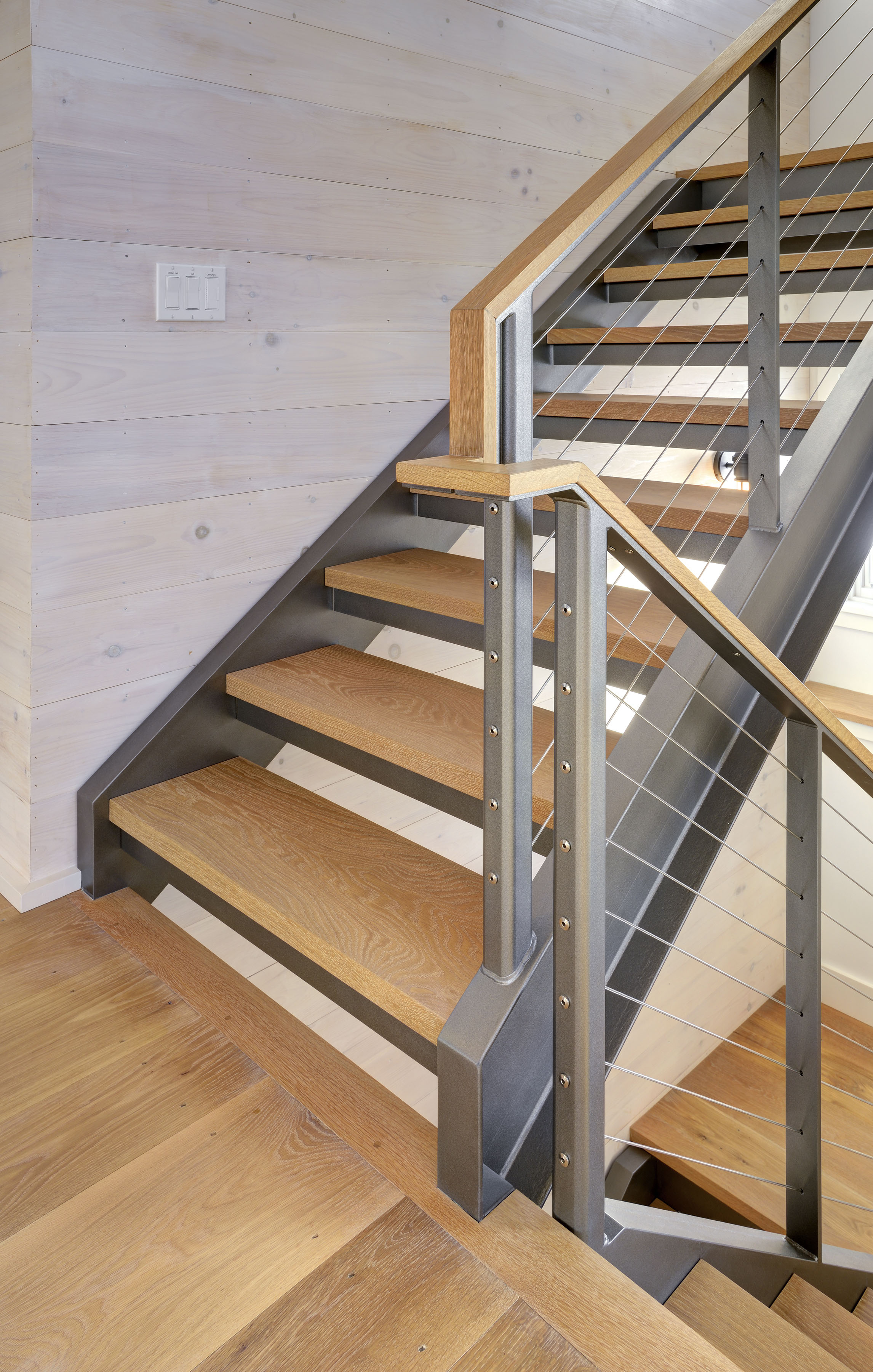 Wood handrail detail on this landing with stainless steel cables 