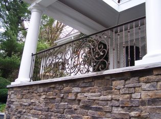 Wrought iron porch railing set between roman tuscan columns