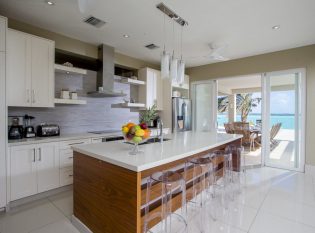 Open white kitchen leading to outdoor dining area.