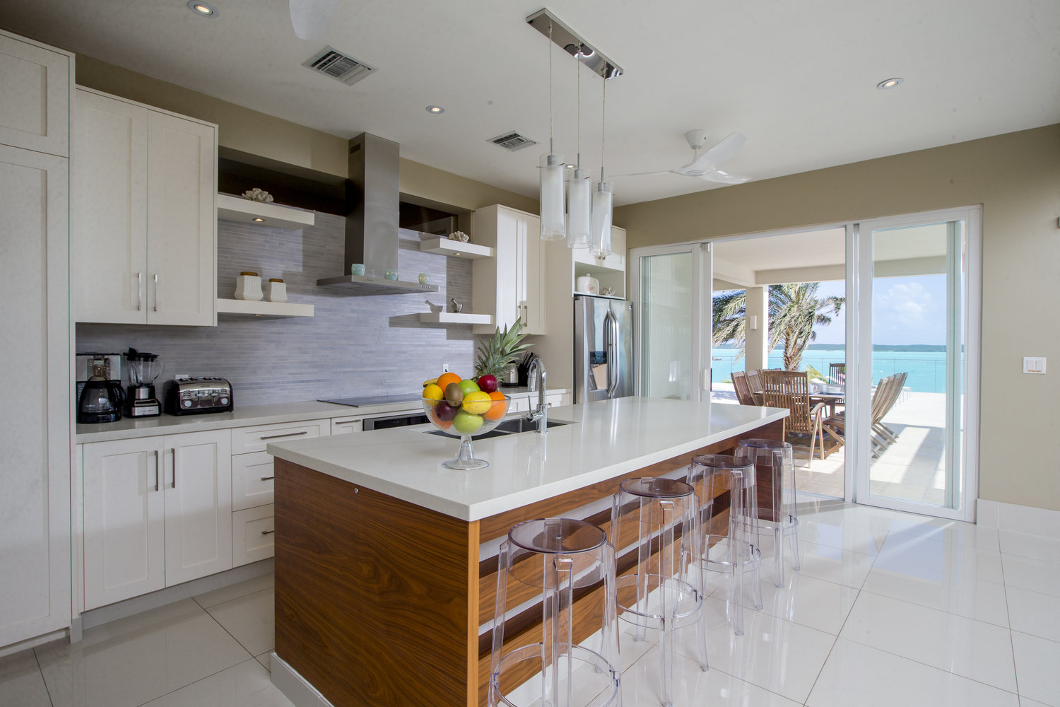 Open white kitchen leading to outdoor dining area.