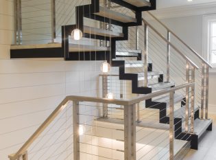 Floating modern staircase with zig zag stringers and stainless steel cable railing