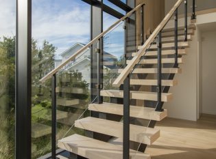 Modern glass staircase railing and floor to ceiling wall of glass