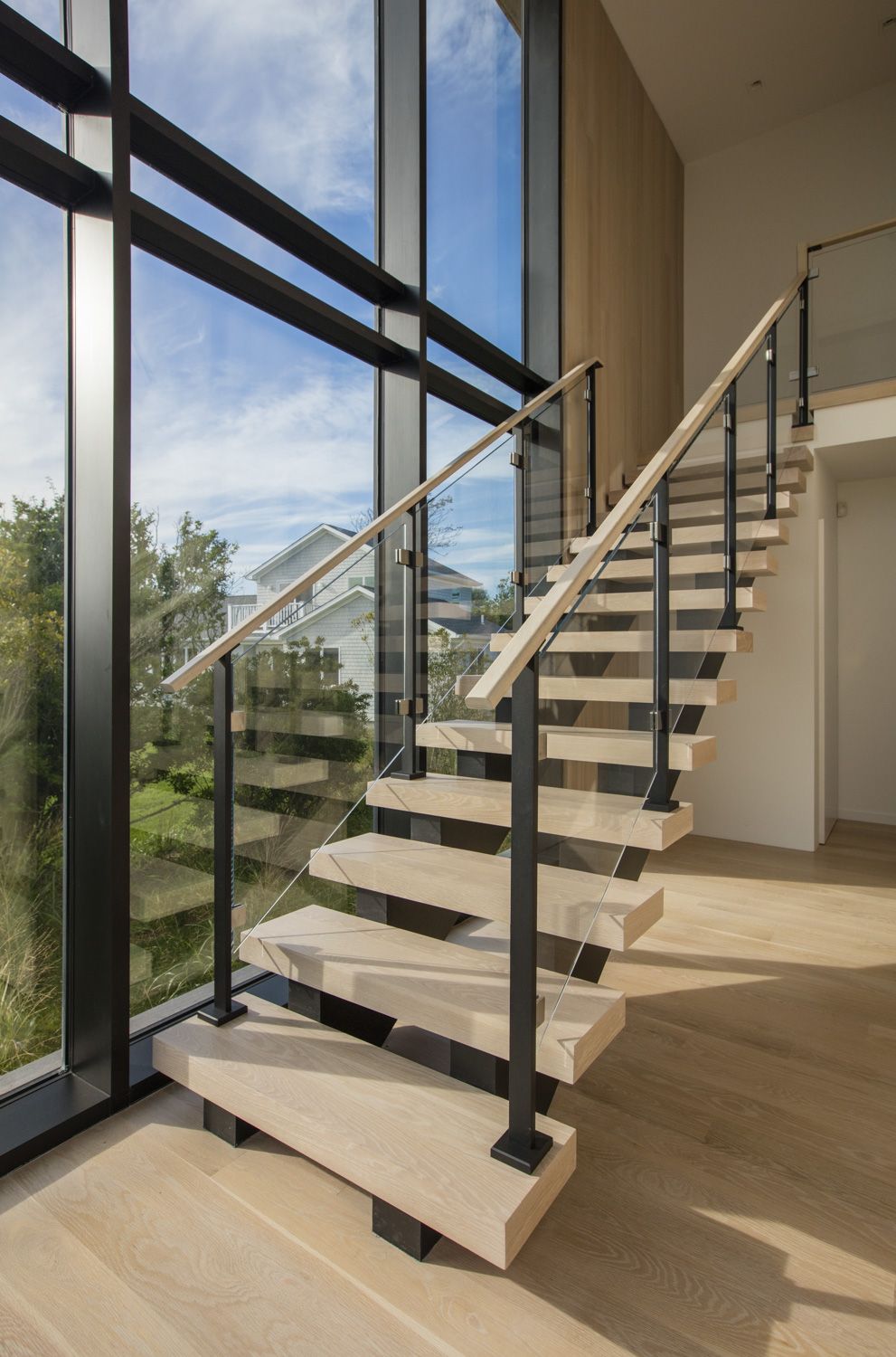 Modern glass staircase railing and floor to ceiling wall of glass