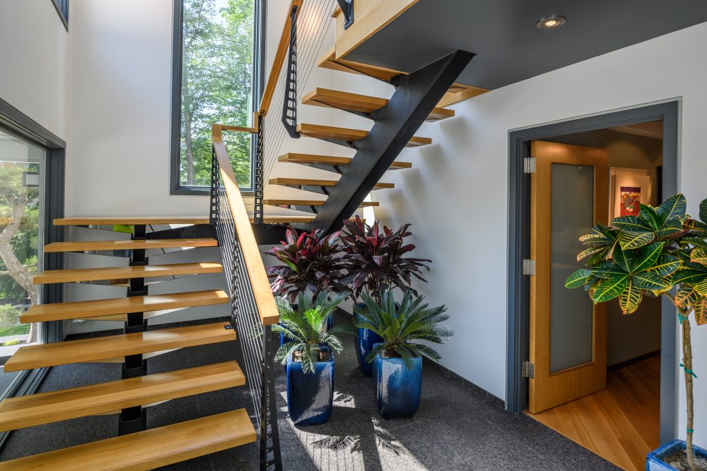 Mono stringer Floating staircase and railing systems in an industrial style with wood treads.