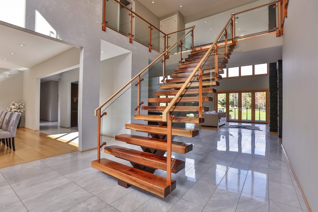 Glass railing on floating mono stringer stairs. The posts and stringer are powder coated a copper color.