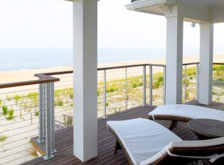 Second-floor exterior balcony with cable railing overlooking the water.