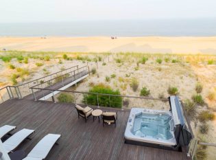 Large oceanfront deck with hot tube and cable railing. 