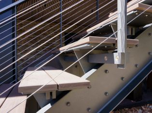 Steel stringer staircase with exposed hardware railing system