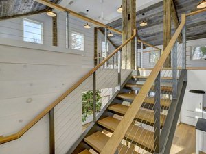 Exposed beam interior with cable railing and floating stairs