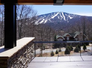 View of snowy Vermont mountains from large cable railing deck