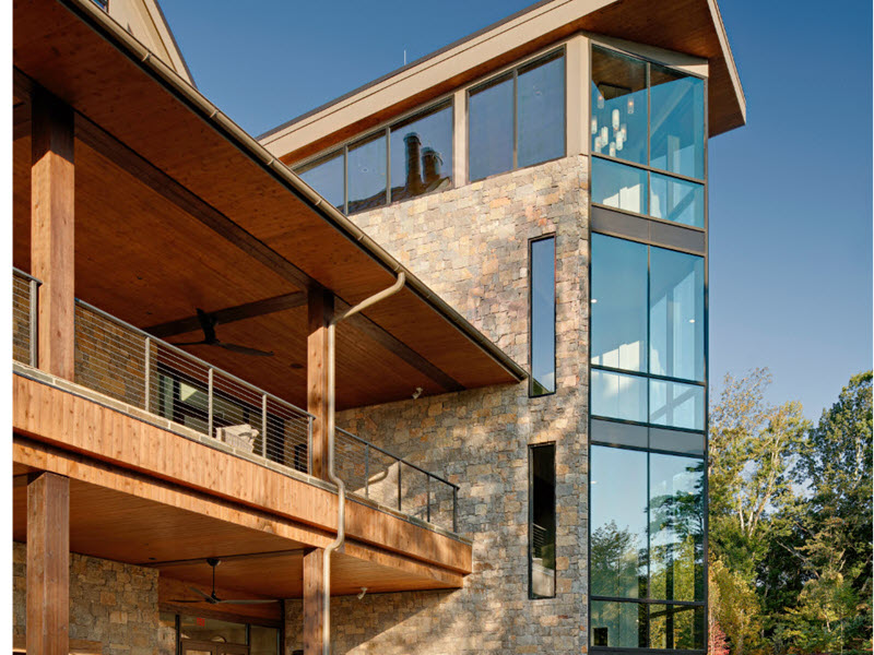 Office event center made of wood and stone with cable railings on the second story the interior stairs beyond the window walls also have cable railings.