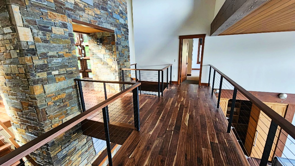 Interior bridge catwalk with cable railing, stone walls and wood floors.