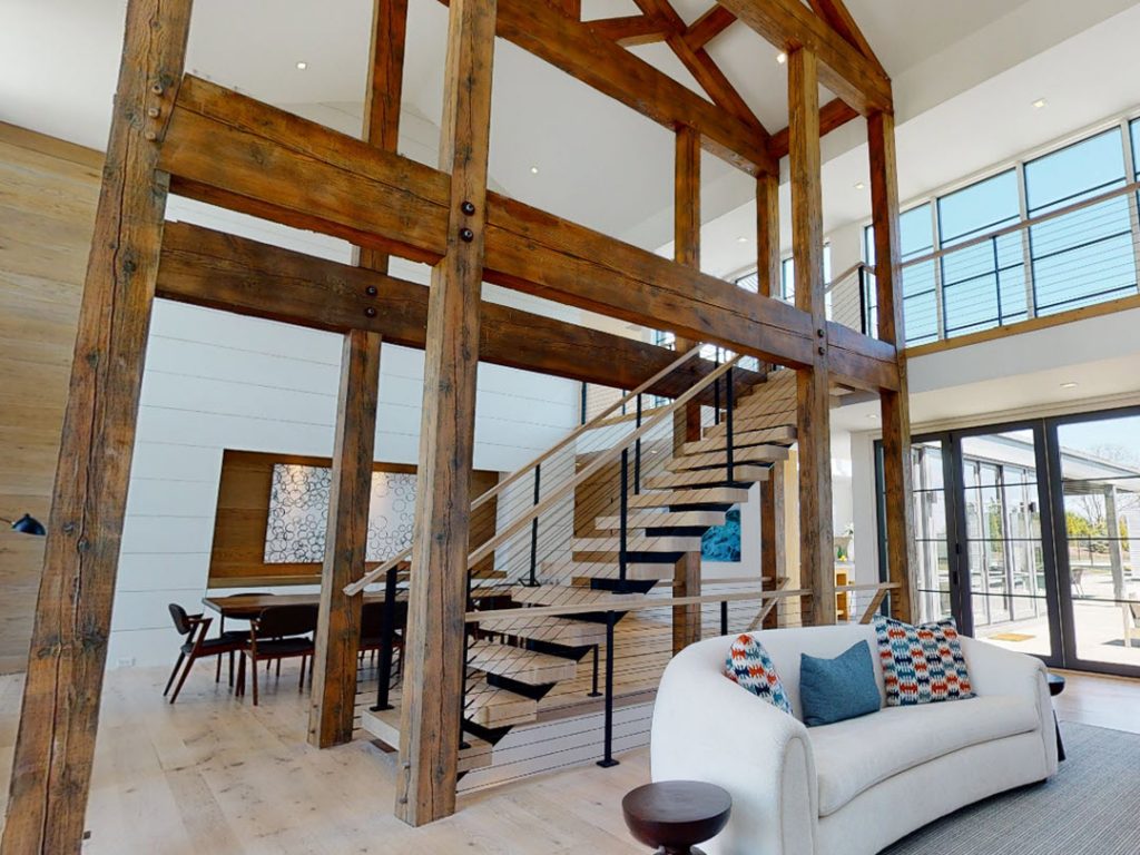 Timber frame structure with floating staircase and cable railings in center of home.