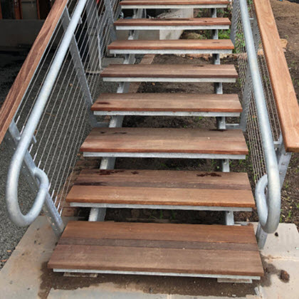 Galvanized railing extending beyond the treads.