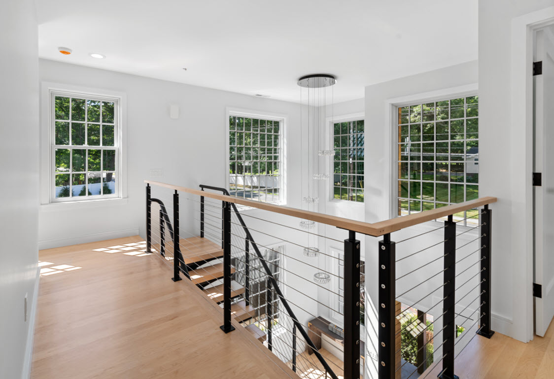 Cable railing on balcony of open concept home at the top of the curved floating stairs