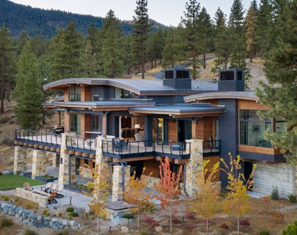 Contemporary Mountain home with curved rooflines and curved cable railings on deck and stone pillars