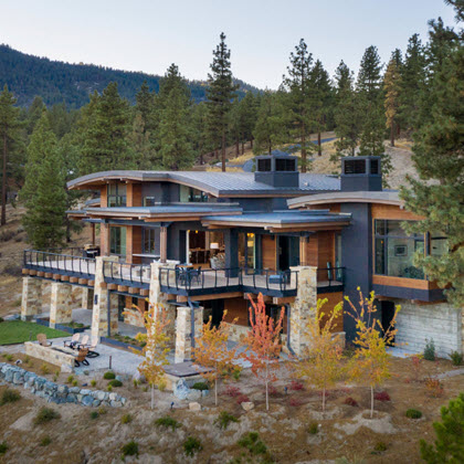 Contemporary Mountain home with curved rooflines and curved cable railings on deck and stone pillars