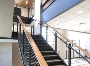Cable railings on office staircase with ADA hand rails and wood top rail.