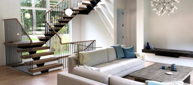 Living room with modern floating spindle stairs and window wall