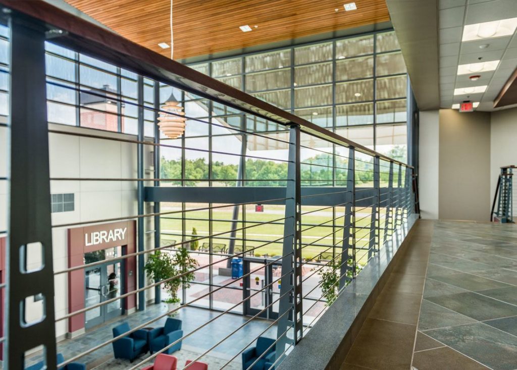 Industrial style railing system with large window view in college atrium.