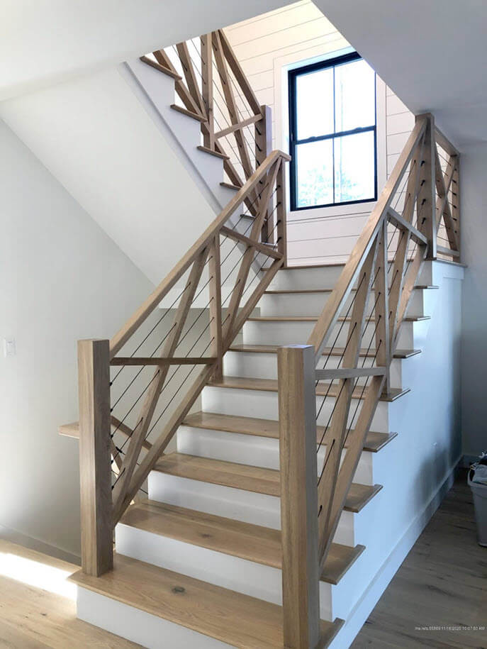 Nautical syle stair with rustic wood railings in a cross pattern and black wire railings.