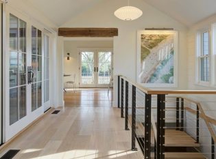 Custom cable railing system wraps open stairwell in homes hallway.