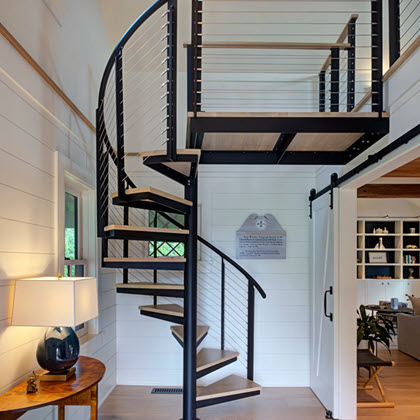 Spiral staircase in entrance of telegraph house with shiplap walls