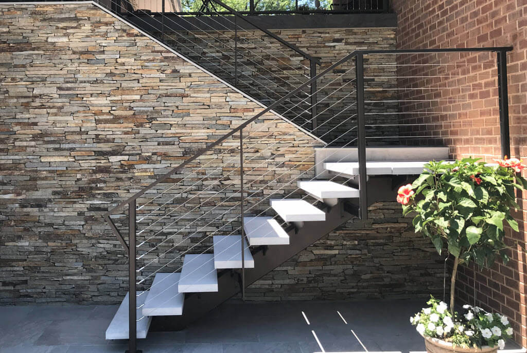 Floating exterior stair with stone steps on brick wall