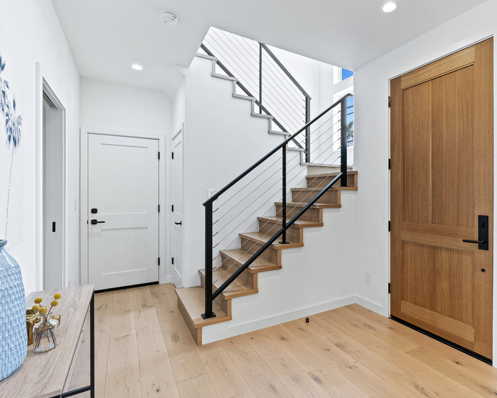 Modern homeas Interior entry has a rustic chic style. The stairs feature wood treads and cable railings. 