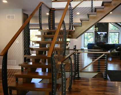 Open stringer stairs with curved cable railings centrally located in the home