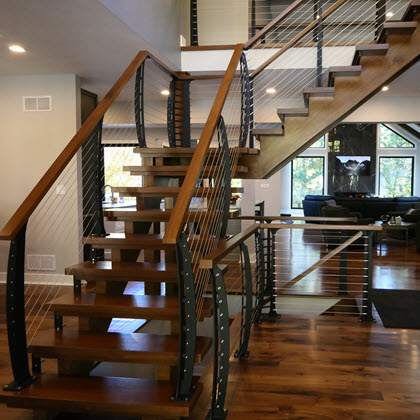 Open stringer stairs with curved cable railings centrally located in the home