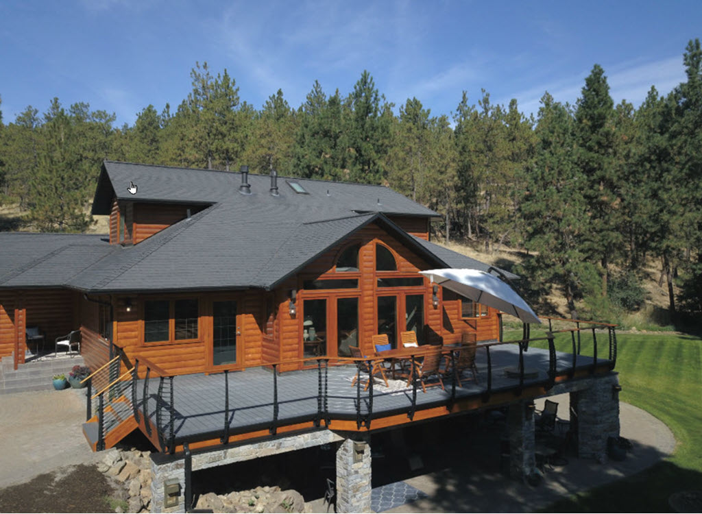 A log home adjacent to the forest curved cable railings system on the exterior.