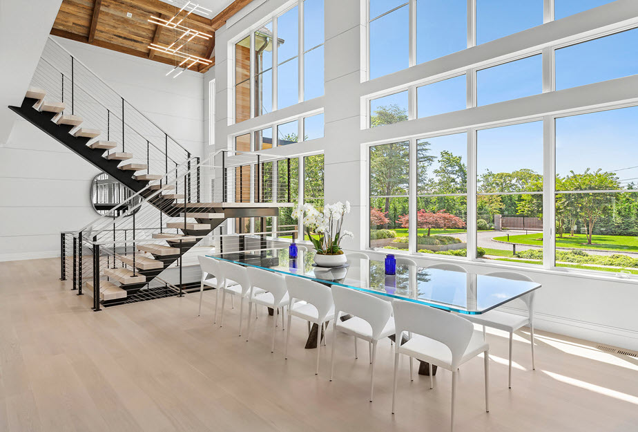 Open dining room with large windows and floating stairs.