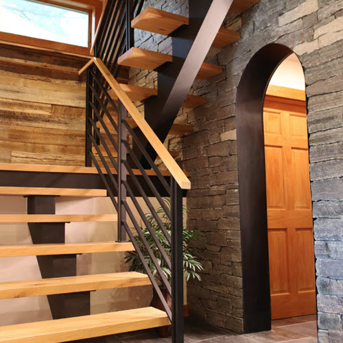 Hollow form floating stair stringer with flat bar railing and white oak treads and handrail in rustic setting.