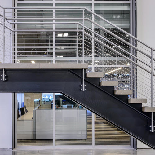 I-Beam stringer stairs with cable railings in industrial building.