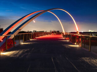 Massive arches light up at night over pedestrian bridge