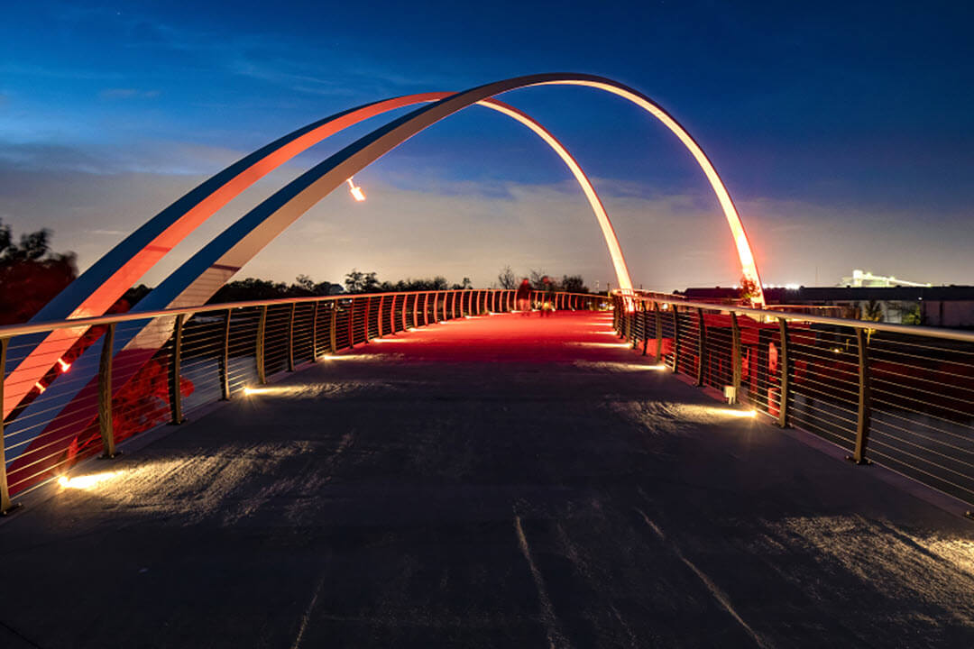 Massive arches light up at night over pedestrian bridge