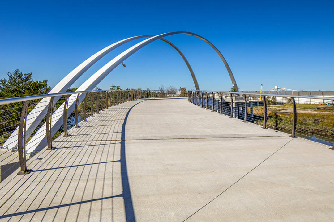 Massive arches on pedestrian bridge with curved cable railing system