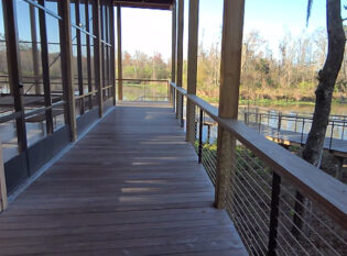 Slim post cable railings wrapping deck of boat house.