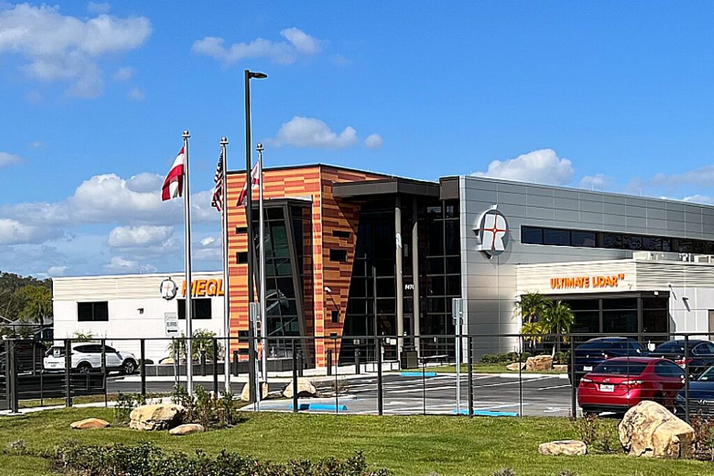 Business office building with tall cable fence, driveway and pedestrian gates 