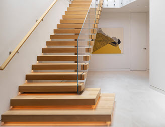 Cantilever stairs in home entrance with wood treads and glass railings in modern home.