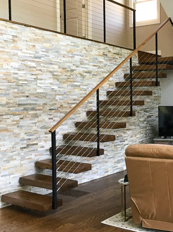Cantilevers Stair with cable railing and hidden support structure in stone wall