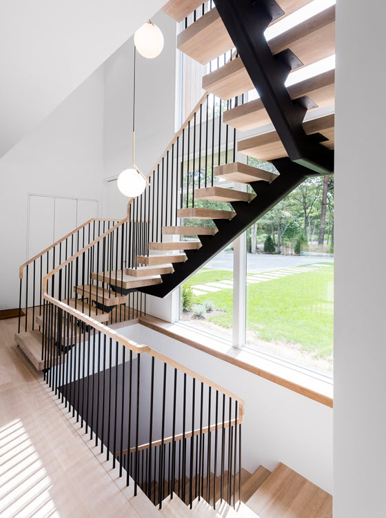 Floating single stringer staircase with spindle railings and wood treads.