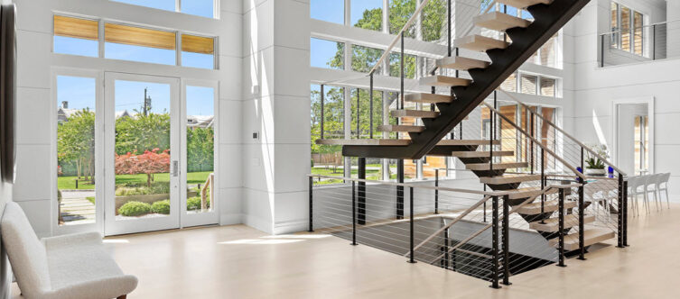floating stiar and cable railing in open concept home with a large window eall
